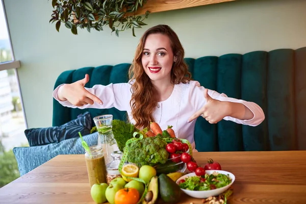 Woman dietitian in medical uniform with tape measure working on a diet plan sitting with different healthy food ingredients in the green office on background. Weight loss and right nutrition concept — Stock Photo, Image