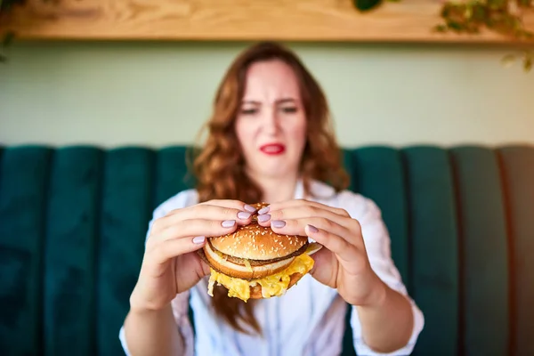 Güzel kadın sağlıksız hamburger yemeyi reddediyor. Ona iğrenerek bakıyor. — Stok fotoğraf