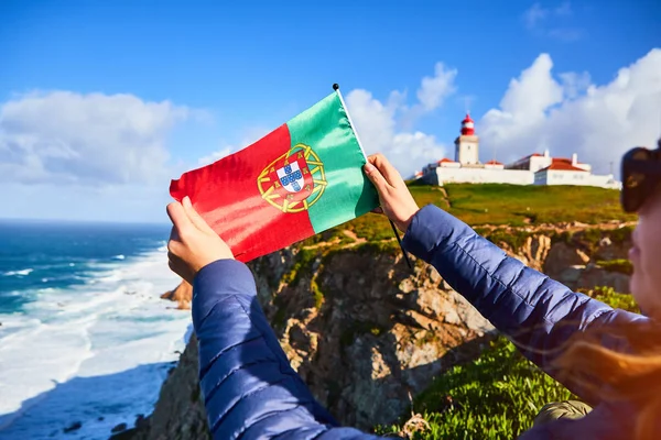 Młoda kobieta turystka na Przylądku Cabo da Roca trzymająca flagę Portugalii z widokiem na piękny krajobraz, zimowa wycieczka. Najbardziej wysunięty na zachód punkt Europy — Zdjęcie stockowe