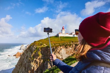 Cape Caba da Roca 'daki güzel genç kadın turist Portekiz' e kış gezisi sırasında cep telefonuyla manzarayı çekiyor. Avrupa 'nın en batı noktası