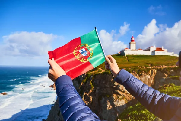 Młoda kobieta turystka na Przylądku Cabo da Roca trzymająca flagę Portugalii z widokiem na piękny krajobraz, zimowa wycieczka. Najbardziej wysunięty na zachód punkt Europy — Zdjęcie stockowe