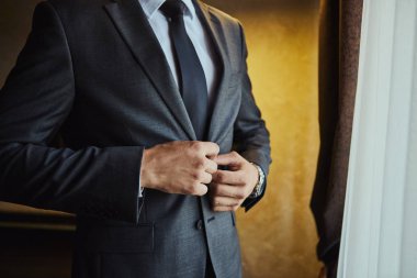 İş adamı ceket giyiyor, erkek eli kapalı, damat düğün töreninden önce hazırlanıyor.