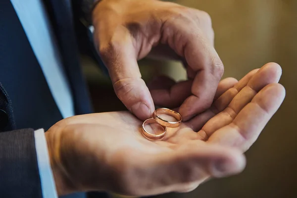 Homem segurando anéis de casamento, noivo se preparando pela manhã antes da cerimônia — Fotografia de Stock