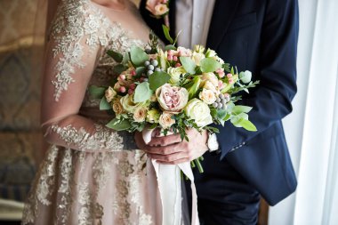 Gelin elinde bir buket ile damadın yanında duruyor.