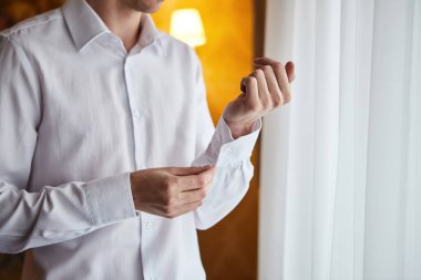 İş adamı beyaz gömlek giyer, erkek eli yakın durur, damat düğün töreninden önce sabah hazırlanır.