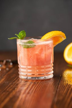 Gri ahşap arka planda greyfurt ve portakallı kokteyl kuyruğu. İçkileri tazeliyorum.