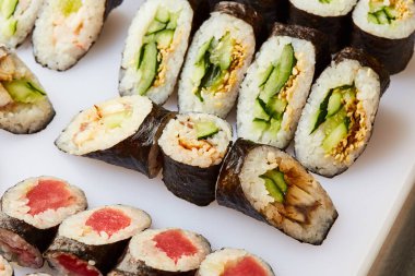 Kesme tahtasında çeşitli suşi ruloları servis ediliyor. Japon yemeği.