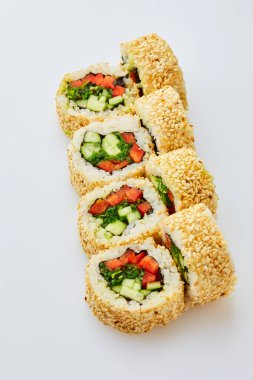 Salatalıklı vejetaryen suşi, tatlı biber ve beyaz arka planda uyanmış yosun.