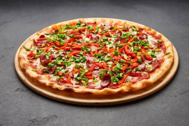 Bol malzemeli pizza: sosis, soğan, peynir ve dolma biber.