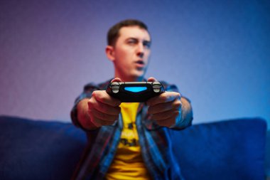 Çılgın oyuncu portresi, video oyunları oynayan çocuk kanepede oturuyor, konsol oyun platformunu elinde tutuyor. Evde dinlenmek, iyi hafta sonları.