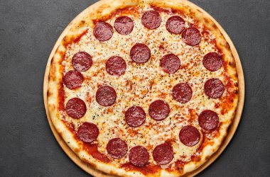 Koyu arkaplanda mozzarella peyniri ve salamlı nefis İtalyan pizzası.