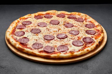 Koyu arkaplanda mozzarella peyniri ve salamlı nefis İtalyan pizzası.