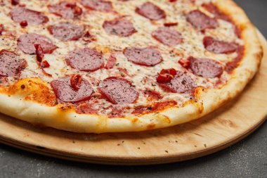 Koyu arkaplanda mozzarella peyniri ve salamlı nefis İtalyan pizzası.