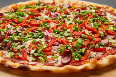 Bol malzemeli pizza: sosis, soğan, peynir ve dolma biber.