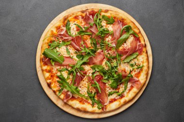 Parma jambonu ve roka ile nefis İtalyan pizzası, koyu arkaplanda mozzarella peyniri.