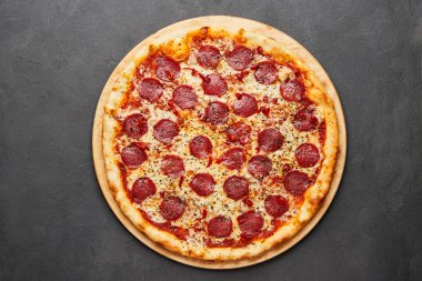 Koyu arkaplanda mozzarella peyniri ve salamlı nefis İtalyan pizzası.