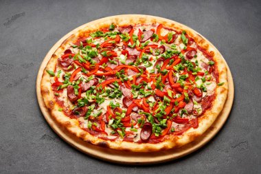 Bol malzemeli pizza: sosis, soğan, peynir ve dolma biber.