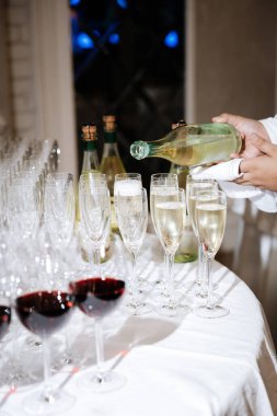 Şenlik kutlamalarında ön planda kırmızı şarapla zarif flütlere şampanya dökmek. Yüksek kalite fotoğraf