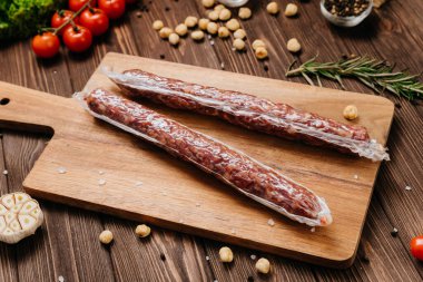 Tahta tahtada kurutulmuş sosisler, baharatlar ve taze sebzeler. Yüksek kalite fotoğraf