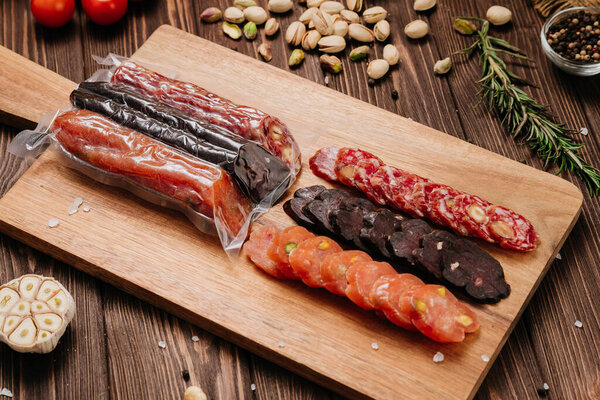 Assorted gourmet sausages sliced and vacuum packed on rustic wooden background with spices. High quality photo