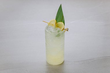 Limon dilimleri ve gri arka planda tiki bardakta buzla tropikal kokteylleri tazeliyorum. Yüksek kalite fotoğraf