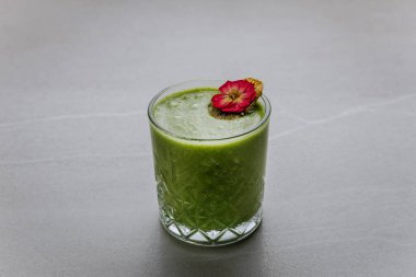 Sağlıklı yeşil smoothie ile kurutulmuş kivi ve gri taş arka planda yenilebilir çiçek. Yüksek kalite fotoğraf