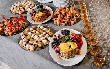 Çeşitli kanepeleri, taze meyveleri ve viski bardakları olan zarif bir yemek masası. Yüksek kalite fotoğraf
