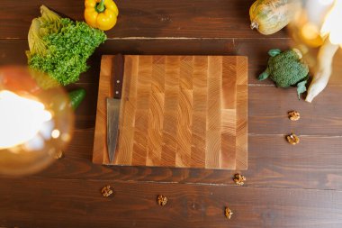 Köy ahşap bir masada taze sebzelerle çevrili bıçakla tahta kesmenin en üst görüntüsü. Yüksek kalite fotoğraf