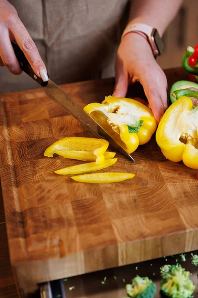 Tahtada sarı dolmalık biber dilimleyen kadın mutfakta taze sebze hazırlıyor. Yüksek kalite fotoğraf