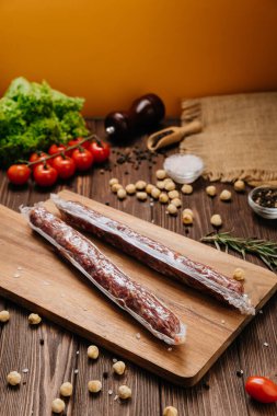 Tahta tahtada kurutulmuş sosisler, baharatlar ve taze sebzeler. Yüksek kalite fotoğraf