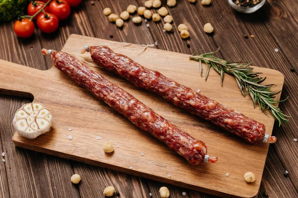 Ahşap kesim tahtasının üzerinde fındık, sarımsak ve biberiye ile sade sosis. Yüksek kalite fotoğraf