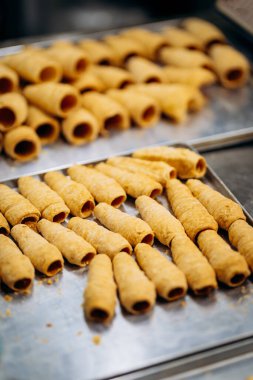 Fırın mutfağında krema doldurmak için tepside pişmemiş hamur işi tüpleri. Yüksek kalite fotoğraf