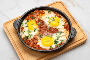 Shakshuka dökme demir tavada, domatesli, otlu ve güneşte pişmiş yumurtalı. Yüksek kalite fotoğraf