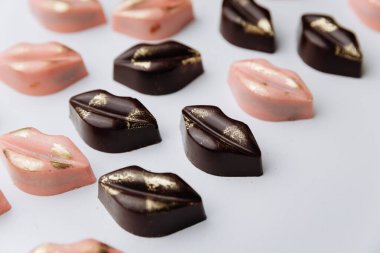 Lüks dudak şekilli çikolata şekerlemeleri ve pastel arka planda altın dekoru. Yüksek kalite fotoğraf