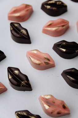 Lüks dudak şekilli çikolata şekerlemeleri ve pastel arka planda altın dekoru. Yüksek kalite fotoğraf