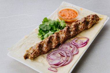 Izgara kuzu kebabı soğan, otlar ve lahanalı ekmek üzerine baharatlı sos. Yüksek kalite fotoğraf