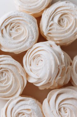 Doğal ışıkta narin beyaz marşmelov tatlısı, havadar dokuya yakın çekim ve kıvrımlı şekil. Yüksek kalite fotoğraf