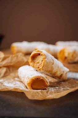 Karamelli kremalı börekler. Parşömen kağıdına pudra şekeri sürülmüş. Yüksek kalite fotoğraf