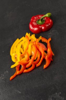 Dilimlenmiş kırmızı ve sarı dolmalık biber, siyah arka planda tam biber, sağlıklı gıda konsepti. Yüksek kalite fotoğraf