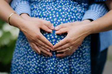 Hamile çift kalp şeklinde el ele tutuşup yeni hayatı kutluyor. Yüksek kalite fotoğraf