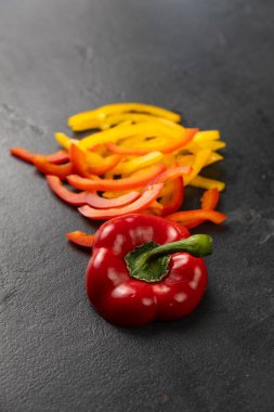 Dilimlenmiş kırmızı ve sarı dolmalık biber, siyah arka planda tam biber, sağlıklı gıda konsepti. Yüksek kalite fotoğraf