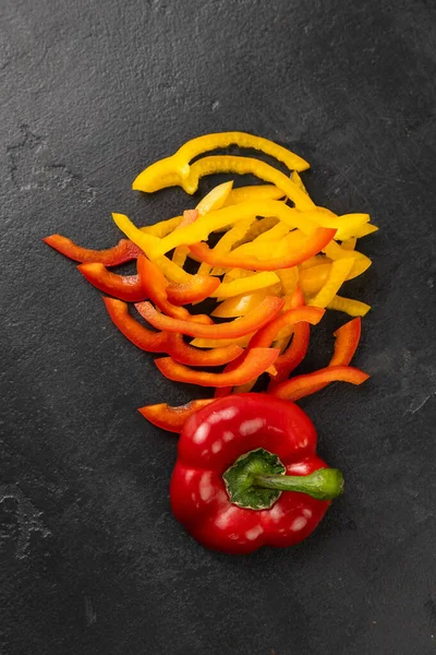 Dilimlenmiş kırmızı ve sarı dolmalık biber, siyah arka planda tam biber, sağlıklı gıda konsepti. Yüksek kalite fotoğraf