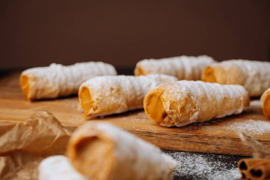 Karamelli kremalı börekler. Parşömen kağıdına pudra şekeri sürülmüş. Yüksek kalite fotoğraf