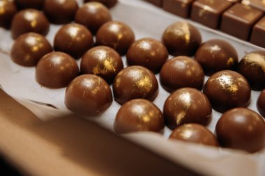 Parşömen kağıdına sıralanmış altın desenli lüks el yapımı çikolatalı bonbonlar. Yüksek kalite fotoğraf