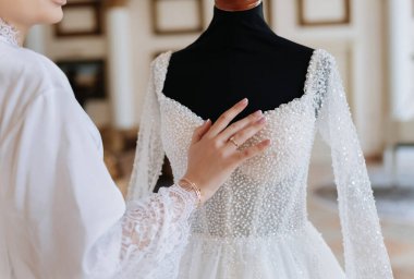 Şık gelin, gelin butiğinde lüks inci gelinliğe dokunuyor. Yüksek kalite fotoğraf