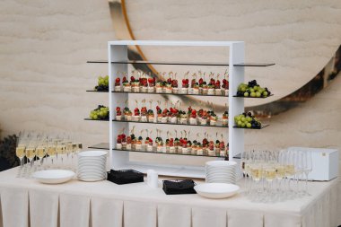 Şölen masasında kanepeler, üzümler ve şampanya kadehleri olan şık bir düğün organizasyonu. Yüksek kalite fotoğraf