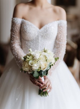 Şık gelin, düğün günü klasik iç mekanda elinde bir buket beyaz gül tutuyor. Yüksek kalite fotoğraf