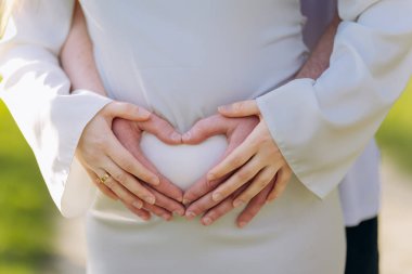 Karın, aşk ve aile kavramı üzerinde kalbe sahip hamile çift baharda açık havada. Yüksek kalite fotoğraf