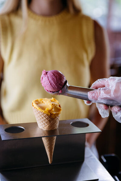 Colorful gelato scoop served in cone by vendor in gloves, summer dessert concept. High quality photo