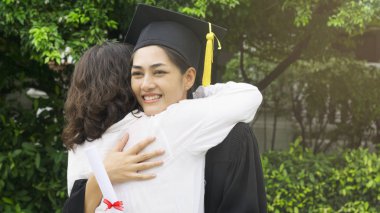 kız öğrenci mezuniyet önlük ve şapka ile sarılmak üst kutlama töreni.